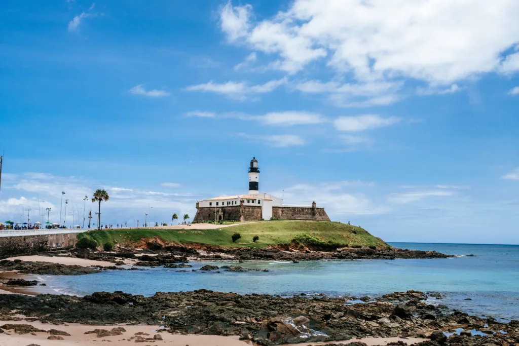 Farol da Barra em Salvador, Bahia, um dos principais pontos turísticos da cidade, com céu azul e mar calmo ao fundo